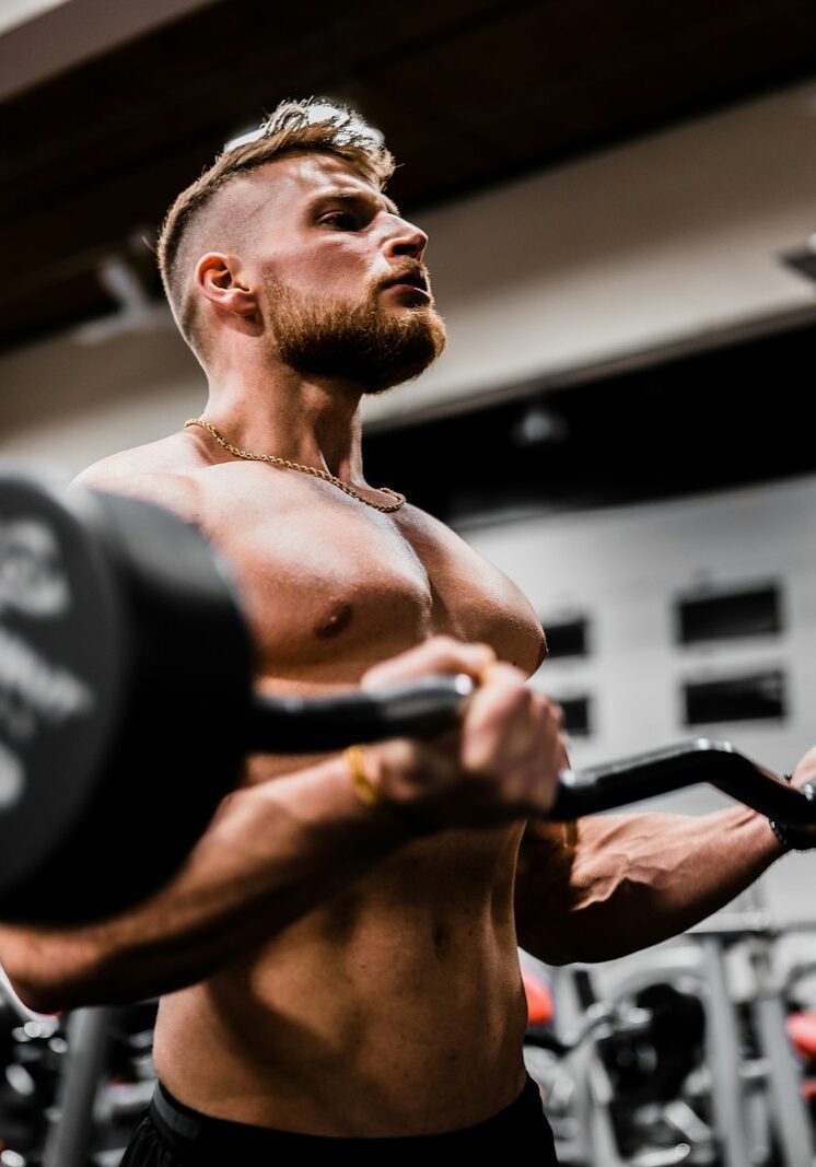 topless man in black shorts carrying black dumbbell